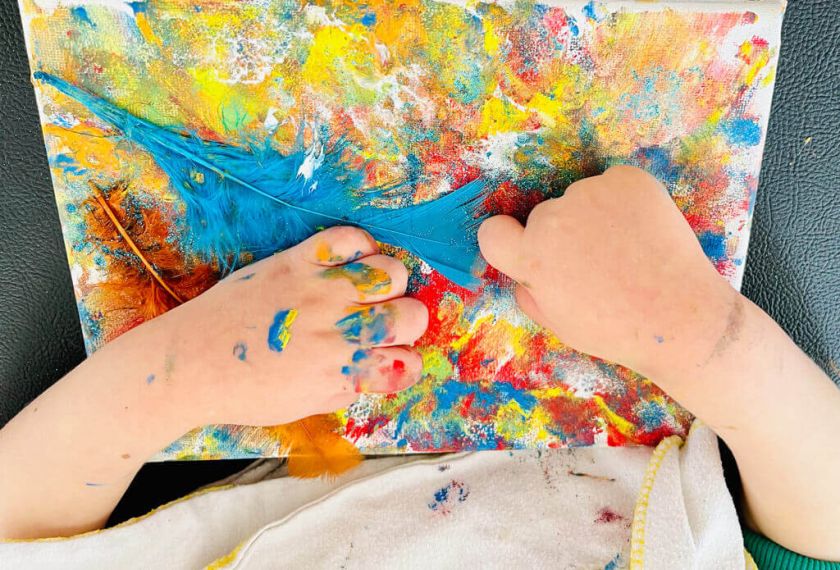 Kinderhände malen ein sehr buntes abstraktes Bild