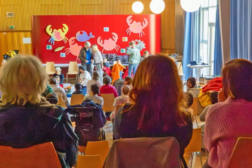 Zuschauende während einer Szene des inklusiven Theaterprojekts Decken.Farben.Jahreszeiten in einem großen Veranstaltungsraum.
