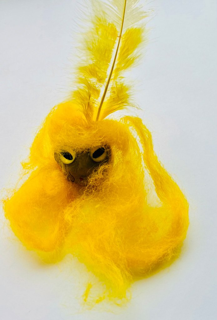 Eine gestaltete Tonkugel, kompiniert mit verschiedenen Materialien, geformt zu einen gelben Monster